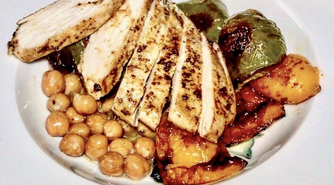 Pierś kurczaka pieczona z warzywami pokrojonymi na kawałki podana z ciecierzycą w sosie z tymiankiem i cytryną.