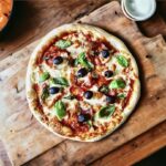 Domowa pizza z salami przygotowana na tradycyjnym cieście podana z domowym sosem pomidorowym z dodatkiem salami, czosnku, oliwek a także świeżej bazylii.