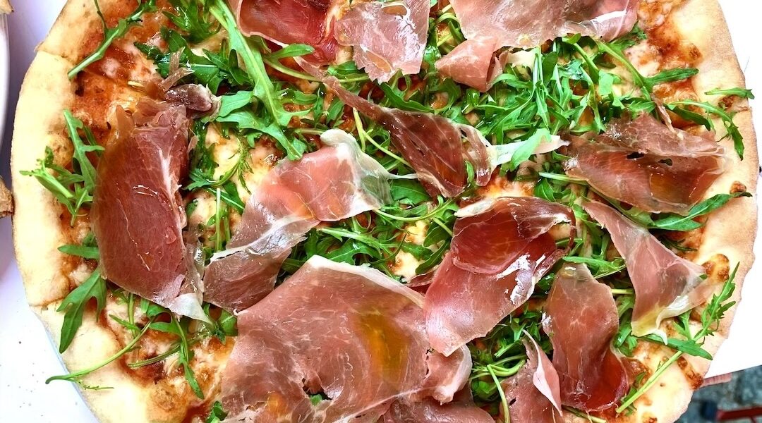 Domowa pizza z pyszną szynką parmeńską i świeżą rukolą.