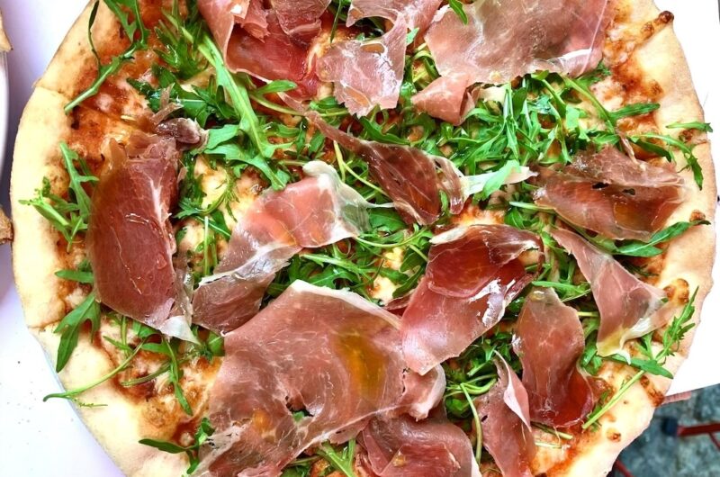 Domowa pizza z pyszną szynką parmeńską i świeżą rukolą.