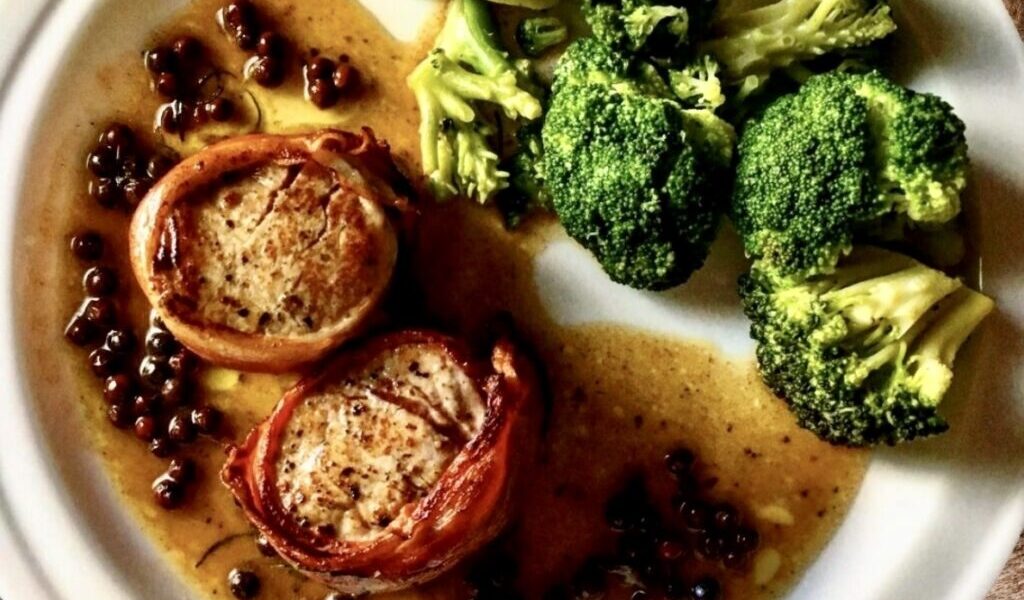 Delikatna polędwiczka wieprzowa owinięta plastrami szynki dojrzewającej, smażona na maśle, a następnie pieczona i podana w sosie z czerwonego pieprzu.