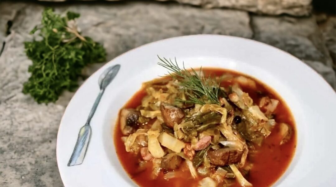 Potrawka z młodej duszonej kapusty z dodatkiem smażonego boczku i grzybów podana w sosie z pomidorów i mielonej papryki.