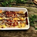 Pstrąg pieczony w całości z kawałkami cytryny oraz z boczkiem i migdałami.