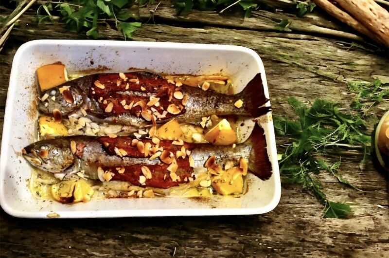 Pstrąg pieczony w całości z kawałkami cytryny oraz z boczkiem i migdałami.