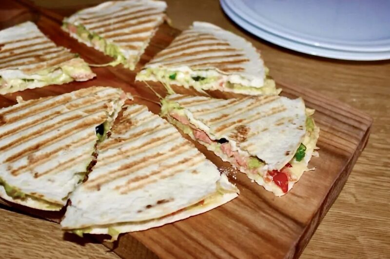 Quesadilla z łososiem to tortilla pokryta puree z awokado podana z łososiem wędzonym, serem i oliwkami a następnie przykryta drugą tortillą i zapieczona.