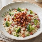 Risotto przygotowane z ryżu duszonego na białym winie i szalotce podane z gotowanym brokułem i smażoną wędzonką.