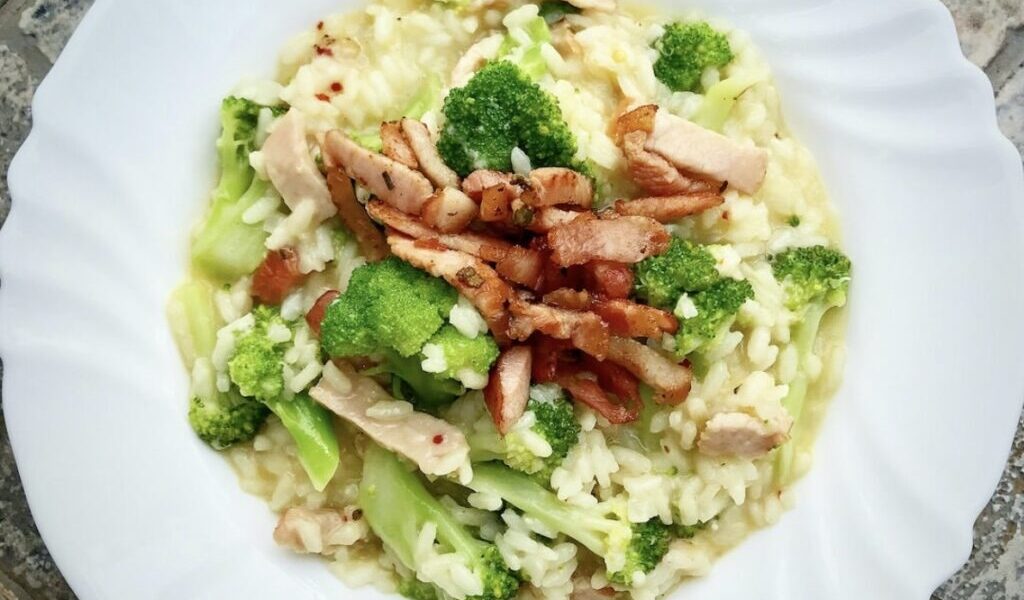 Risotto przygotowane z ryżu duszonego na białym winie i szalotce podane z gotowanym brokułem i smażoną wędzonką.