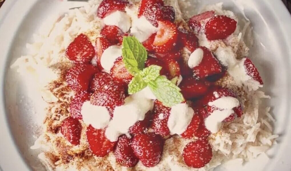 Pyszny i aromatyczny ryż z dojrzałymi truskawkami i cynamonem polany kwaśną śmietaną.