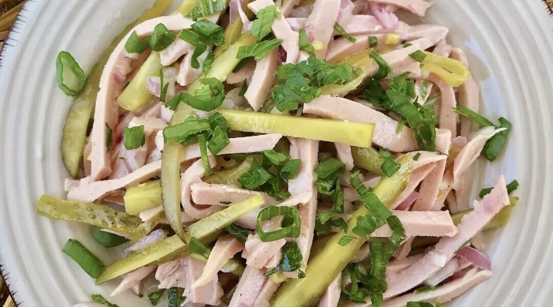Prosta sałatka bawarska z krojoną mortadelą z dodatkiem ogórków konserwowych i cebuli polana kwaśnym sosem.
