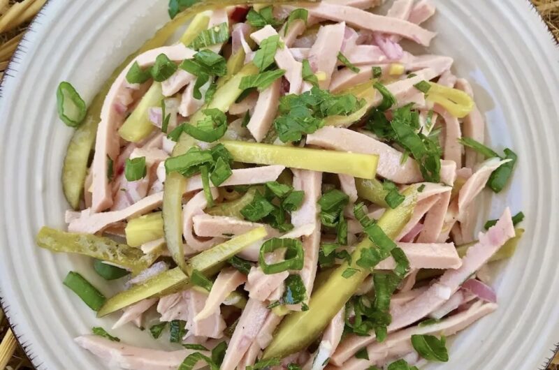 Prosta sałatka bawarska z krojoną mortadelą z dodatkiem ogórków konserwowych i cebuli polana kwaśnym sosem.