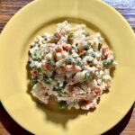 Sałatka jarzynowa z gotowanych i krojonych warzyw korzeniowych z dodatkiem groszku, jajek i ogórków kiszonych połączonych majonezem.