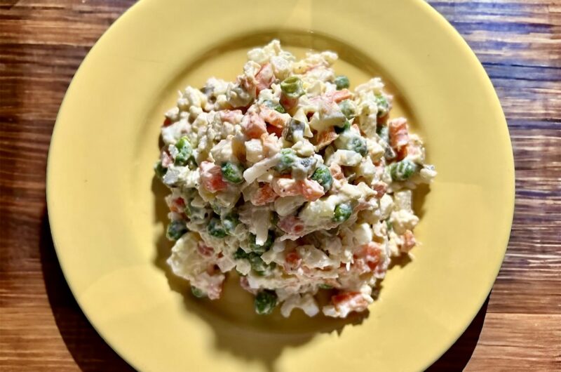 Sałatka jarzynowa z gotowanych i krojonych warzyw korzeniowych z dodatkiem groszku, jajek i ogórków kiszonych połączonych majonezem.