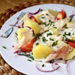 Sałatka z gotowanymi ziemniakami sałatkowymi i pstrągiem wędzonym podana z dipem szczypiorkowym.