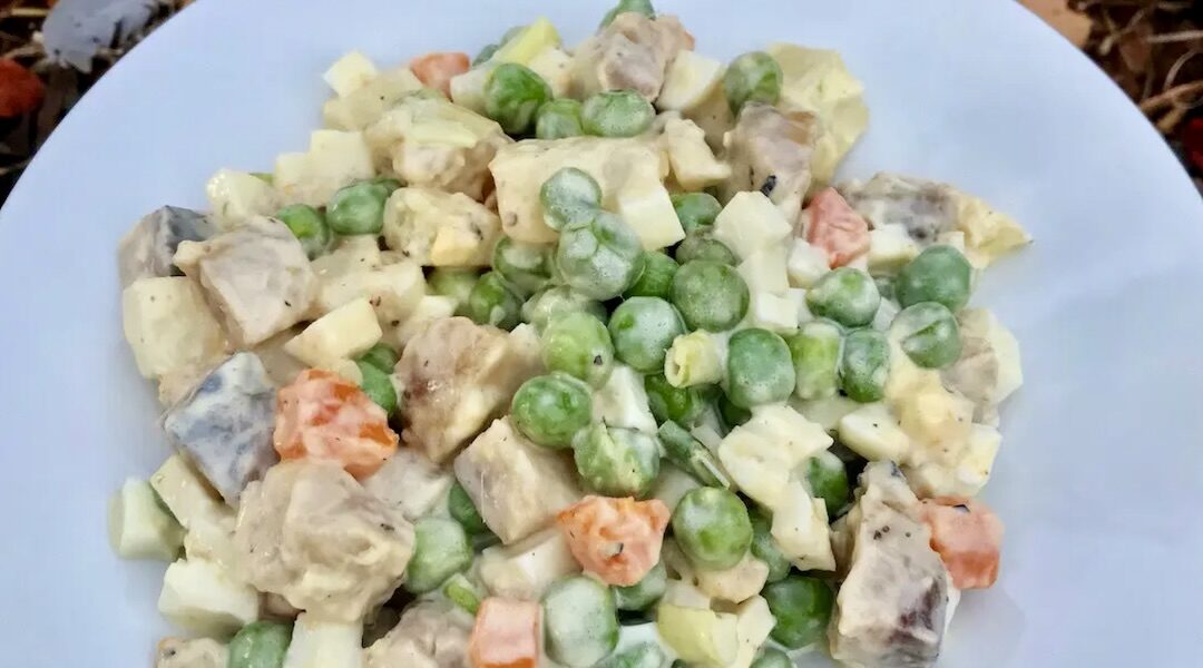 Sałatka przygotowana ze śledziem wędzonym, groszkiem, gotowanym jajkiem i ziemniakami połączona majonezem.