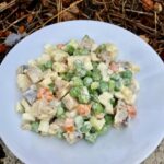 Sałatka przygotowana ze śledziem wędzonym, groszkiem, gotowanym jajkiem i ziemniakami połączona majonezem.