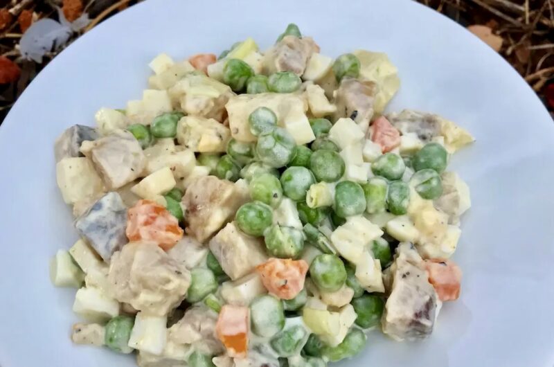 Sałatka przygotowana ze śledziem wędzonym, groszkiem, gotowanym jajkiem i ziemniakami połączona majonezem.