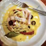 Śledź matjas pokrojony w cienkie paski i zatopione w oleju razem z oliwkami, kaparami i suszonymi pomidorami.