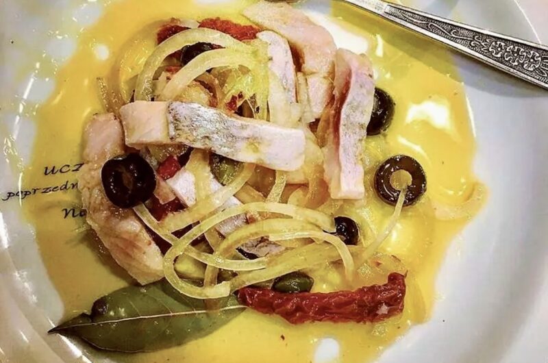 Śledź matjas pokrojony w cienkie paski i zatopione w oleju razem z oliwkami, kaparami i suszonymi pomidorami.