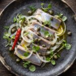 Śledzie pokrojone w małe kawałki, następnie polane olejem i podawane z kaparami, cebulą i papryczkami chilli na ostro.