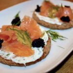 Kanapki szwedzkie przygotowane z sucharków posmarowanych serkiem i obłożonych łososiem wędzonym podane z sosem musztardowym z koperkiem.