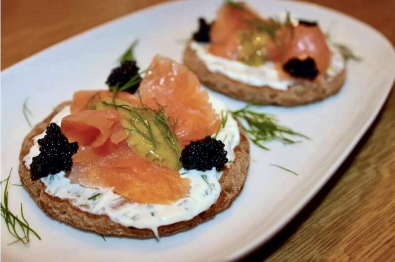 Kanapki szwedzkie przygotowane z sucharków posmarowanych serkiem i obłożonych łososiem wędzonym podane z sosem musztardowym z koperkiem.