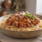 Makaron spaghetti podany z sosem alla bolognese przygotowanym z mięsa mielonego duszonego w sosie pomidorowym.