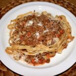 Makaron spaghetti podany z sosem alla bolognese przygotowanym z mięsa mielonego duszonego w sosie pomidorowym.