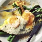 Krótko gotowane zielone szparagi podane z jajkiem sadzonym posypane świeżo startym serem parmezan.