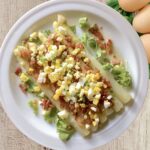 Ugotowane białe szparagi podane z przesmażoną szynką oraz startym gotowanym jajkiem.