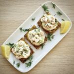 Tartinki bankietowe to kawałki ciemnego pieczywa podane z krewetkami przygotowanymi w formie sałatki, a także z ogórkiem i cebulą połączone majonezem z dodatkiem koperku.