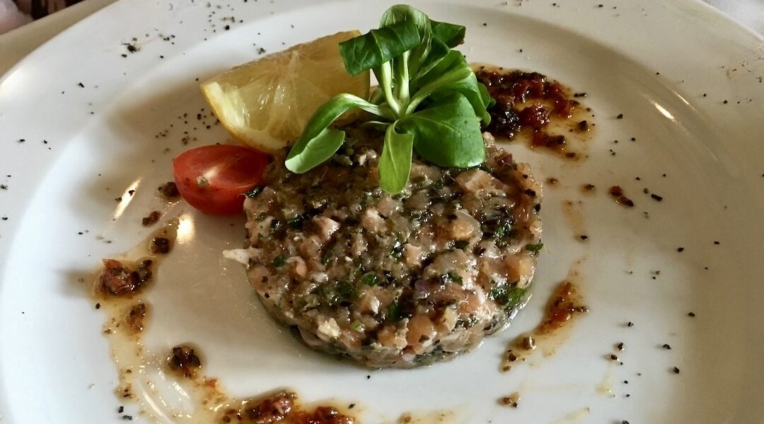 Tatar przygotowany z siekanego łososia wędzonego na zimno z dodatkiem kaparów, oliwek, korniszonów i cebuli