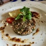 Tatar przygotowany z siekanego łososia wędzonego na zimno z dodatkiem kaparów, oliwek, korniszonów i cebuli