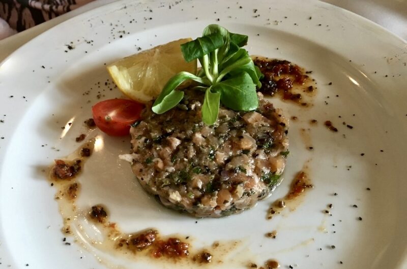 Tatar przygotowany z siekanego łososia wędzonego na zimno z dodatkiem kaparów, oliwek, korniszonów i cebuli