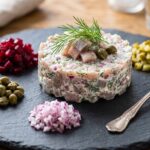 Tatar z matjasa holenderskiego przygotowany z dodatkiem śmietany i koperku podany.