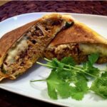 Tortilla z ugotowanym wcześniej kurczakiem z dodatkiem cebuli i czerwonej fasolki, a następnie zawinięta ze startym serem i kolendrą.