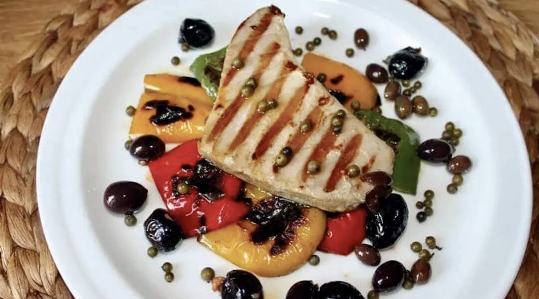 Pieczony na ruszcie tuńczyk z grilla podany z warzywami grillowanymi skropionymi oliwą.