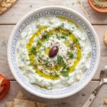 Tzatziki to sos grecki przygotowany z gęstego pełnotłustego jogurtu z dodatkiem startych i odciśniętych świeżych ogórków doprawiony czosnkiem, octem winnym, oliwą i świeżym koperkiem.