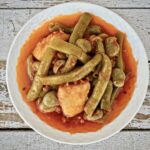 Warzywa w postaci ziemniaków, fasolki szparagowej i bobu duszone z cebulą i czosnkiem w sosie pomidorowym.