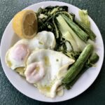 Gotowane warzywa czyli cykoria, cukinia i por podane z jajkiem sadzonym i w całości polane oliwą i sokiem z cytryny.