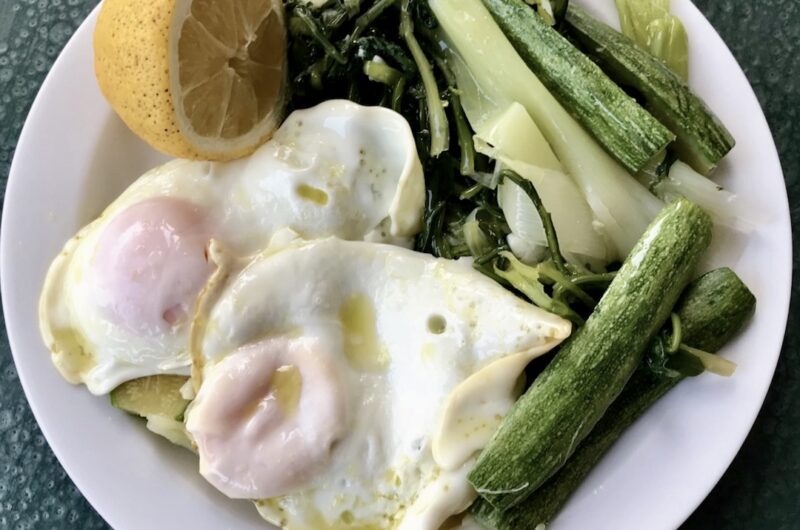 Gotowane warzywa czyli cykoria, cukinia i por podane z jajkiem sadzonym i w całości polane oliwą i sokiem z cytryny.