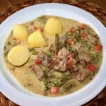 Gulasz cielęcy z mięsa krojonego w kostkę, a następnie duszonego z szynką, marchewką i szparagami na koniec doprawiony słodką śmietanką.