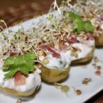 Ziemniaki z piekarnika polane dipem jogurtowym i obłożone szynką szwarcwaldzką, fetą, kiełkami i słonecznikiem.