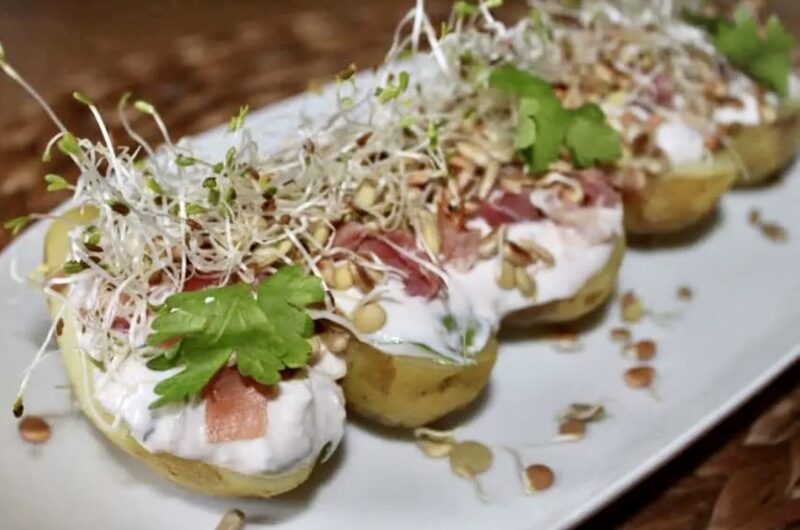 Ziemniaki z piekarnika polane dipem jogurtowym i obłożone szynką szwarcwaldzką, fetą, kiełkami i słonecznikiem.