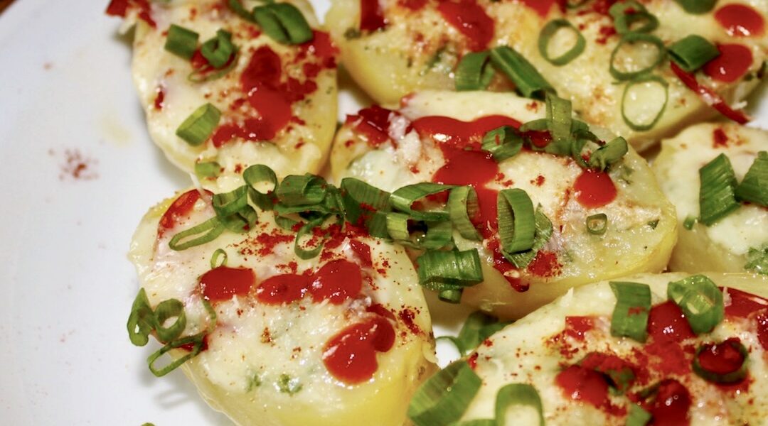 Ziemniaki gotowane w całości, a następnie przekrojone na pół i zapiekane z dodatkiem masła czosnkowego oraz sera i chili.