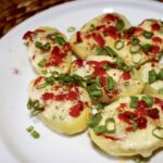 Ziemniaki gotowane w całości, a następnie przekrojone na pół i zapiekane z dodatkiem masła czosnkowego oraz sera i chili.