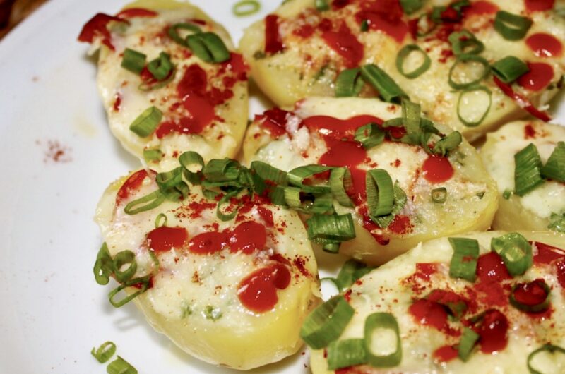 Ziemniaki gotowane w całości, a następnie przekrojone na pół i zapiekane z dodatkiem masła czosnkowego oraz sera i chili.