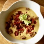 Aromatyczna zupa krem z kalafiora przyrządzona na wywarze jarzynowym z dodatkiem sera, podana z grzankami i chrupiącą szynką.