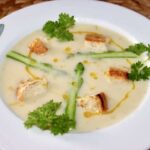 Zupa krem przygotowana z gotowanych białych szparagów doprawiona słodką śmietanką, a następnie zmiksowana i podana z zielonymi szparagami oraz grzankami.