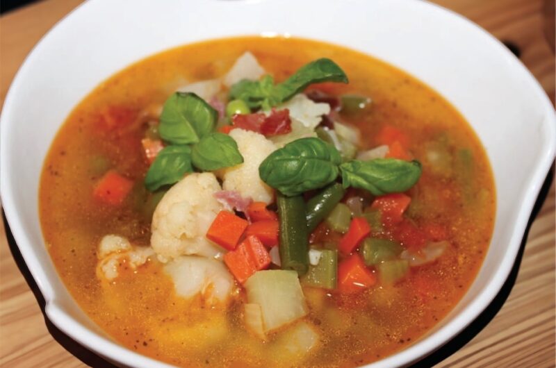 Zupa minestrone, czyli włoska zupa jarzynowa w wersji zimowej przygotowana na domowym bulionie drobiowym zrobiona na soffritto i z dodatkiem mrożonych warzyw.