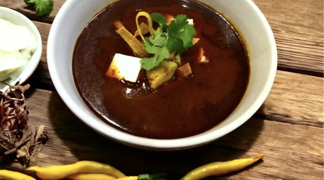 Zupa paprykowa przyrządzona z papryczek suszonych zmiksowanych z grillowanymi pomidorami i cebulą podana z tortillą pokrojoną w paski.